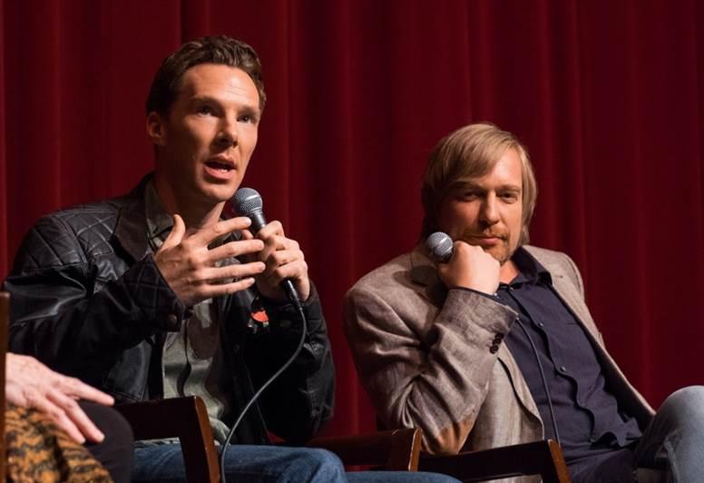 Cumberbatch con una chaqueta de cuero negra habla por un micrófono mientras Tyldum con una chaqueta de color claro y un botón oscuro escucha con la cabeza apoyada en el puño.
