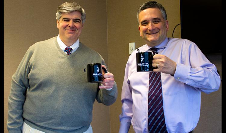 Jim Russ, reportero jefe de tráfico de WBAL-AM, y Robert Lang, presentador / reportero legislativo y político, sostienen dos tazas de café con el logotipo de SAG-AFTRA.