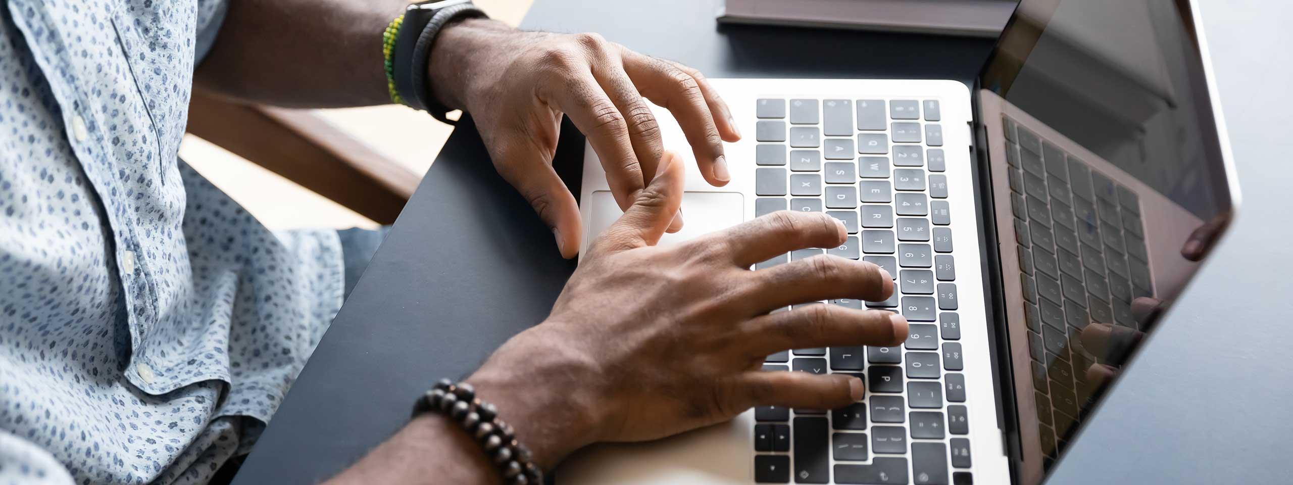 Imagen de un hombre escribiendo en una computadora portátil.