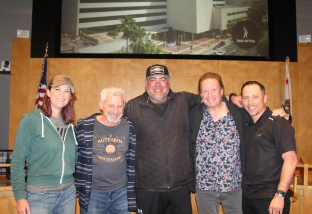 From left, Fink, Vitale, Williams, Ryan and Bouciegues pose in an auditorium. All are dressed in casual clothing: T-shirts, hoodies and jeans. Fink and Williams both wear sports hats.