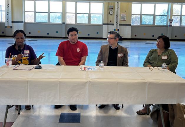 Cuatro panelistas se sientan en una mesa en una sala grande.