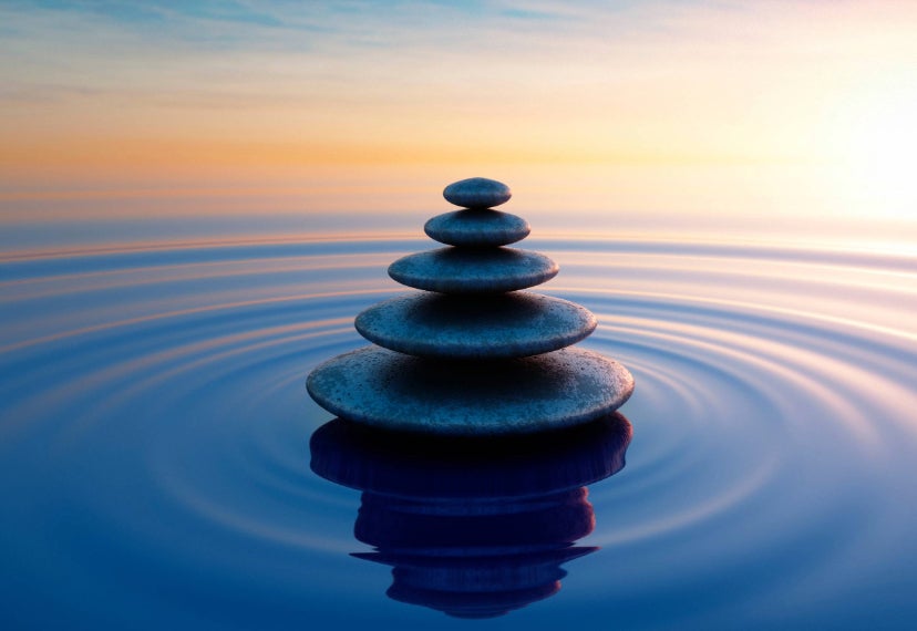 Una fotografía de piedras de meditación en un cuerpo de agua tranquilo.
