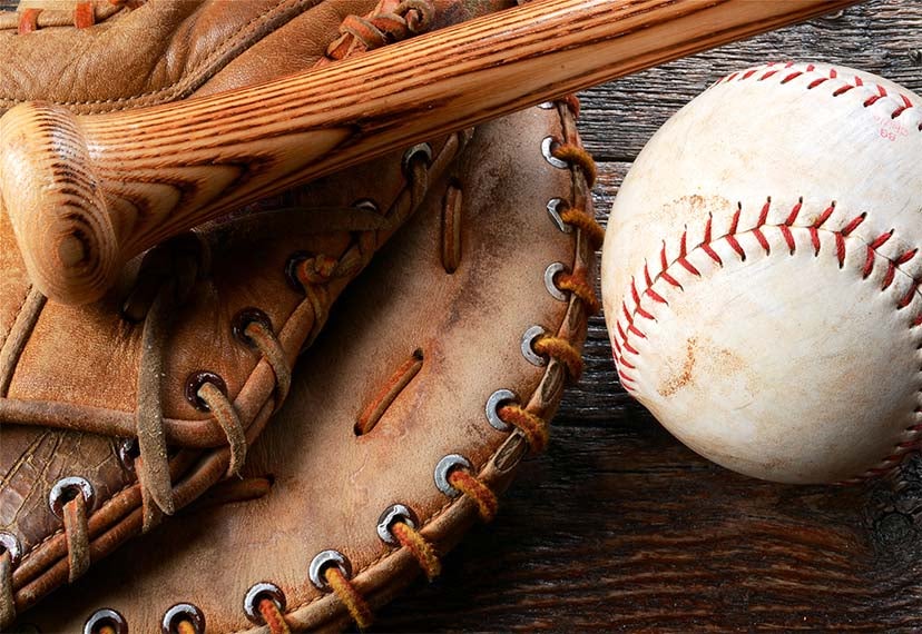 A baseball bat lays on a baseball glove and a baseball is next to it. 