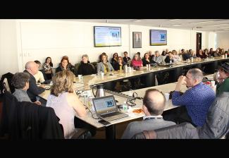 Un gran grupo de personas sentadas alrededor de una mesa dentro de una sala de conferencias en Nueva York.