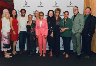 Eleven individuals take a group photo in front of a white SAG-AFTRA step-and-repeat backdrop.