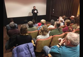 SAG-AFTRA Seattle Local President Rik Deskin stands in front of group of seated individuals in a small movie theater. 