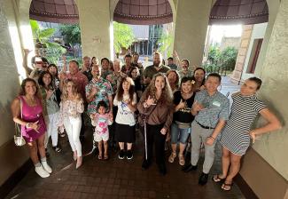 Hawaii Local members and industry leaders pose in an alcove in front of three arches that lead outside. Many of those in the photo are throwing a shaka and smiling.