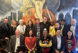 The group of union leaders pose against a mural of a city skyline.