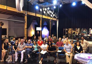 group photo of performers inside a theater like room