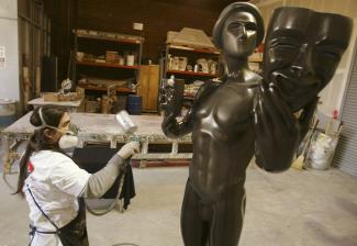 A woman sprays a big Actors statuette.