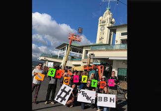Hawaii Local members with colorful signs at the Aloha Tower on Dec. 13.