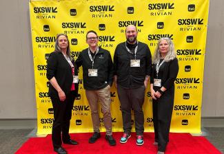 Four individuals on the red carpet in a nondescript room. Behind them is a yellow step-and-repeat backdrop with the SXSW logo.