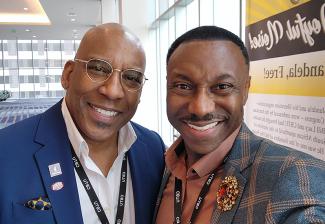 Una foto estilo selfie de Joseph y Knight. Joseph lleva un blazer de franela azul y marrón con un broche y una camisa de color óxido; Knight lleva un blazer azul marino con dos prendedores esmaltados y una camisa de vestir blanca.