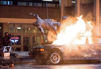 Male stunt performer is teethered above a car on fire on the set of CW's "The Flash."