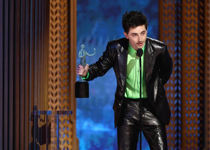 Timothee Chalamet stands on stage. Beside him is the SAG Awards statuette.