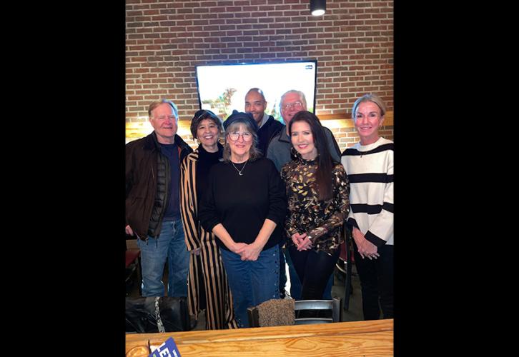 A group photo of seven individuals in a bar or restaurant setting.