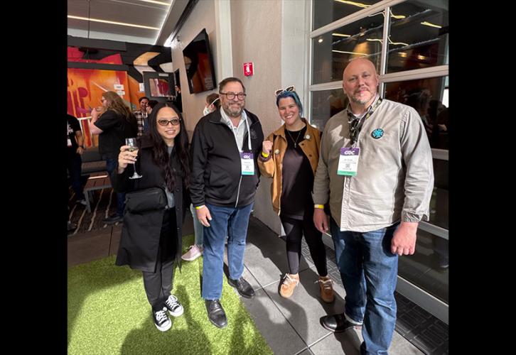 Four individuals take a group photo inside a brightly lit recreational space.