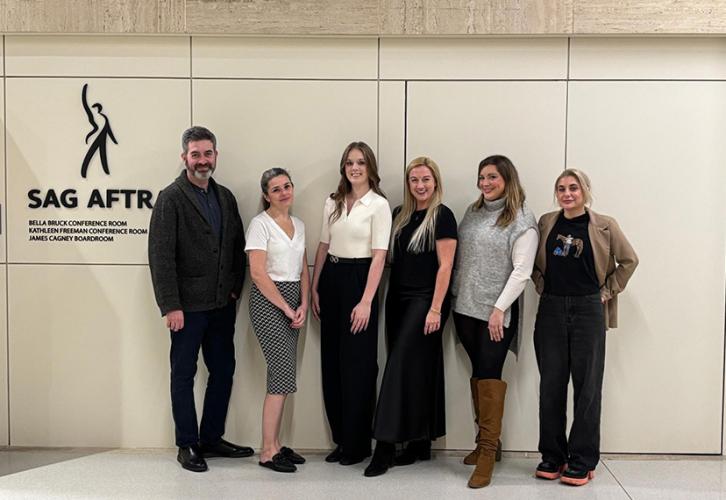 Six individuals stand by a wall with a SAG-AFTRA logo to the left of the group. 