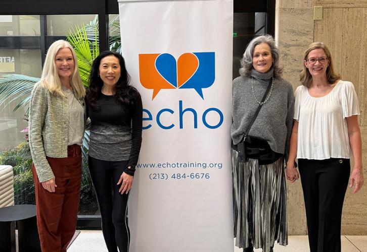 Four individuals stand around a sign with the “Echo” logo on it in orange and blue with a white background. 