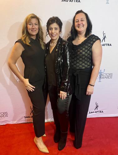 Bazarian, Levine and Crowley Kwaitowski stand closely together on the red carpet. All wear black; Bazarian’s shoes are a nude color. Behind them is a white SAG-AFTRA and SAG Awards step-and-repeat backdrop.