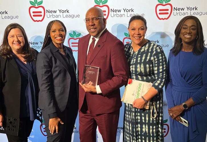 Damon, Byfield (African American), Knight (African American), Powell (African American) and Beckford (African American) stand for a photo. The group is arranged in front of a white NYUL backdrop.