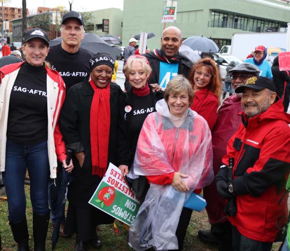 Group shot of members wearing SAG-AFTRA shirts and raincoats