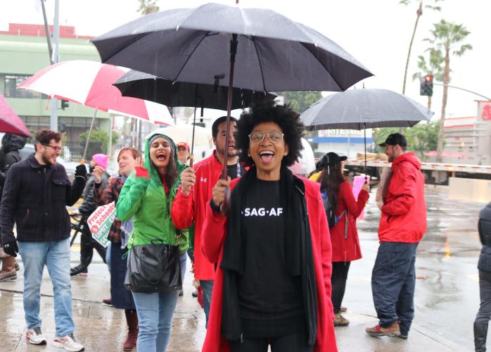 SAG-AFTRA member holding an umbrella and chanting along with the crowd