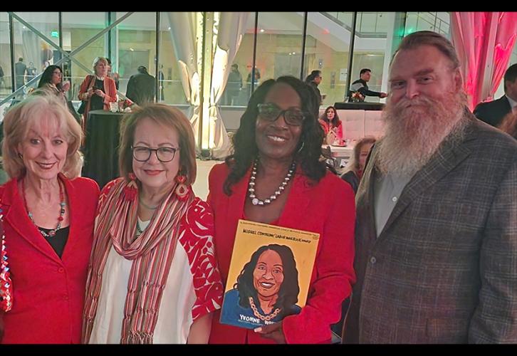 Crawford, Durazo (Latina), Wheeler (Black) and Scullin take a group photo inside a reception area. The women wear red; Scullin wears a gray-patterned blazer. Wheeler displays a magazine with an illustration of herself on the cover.