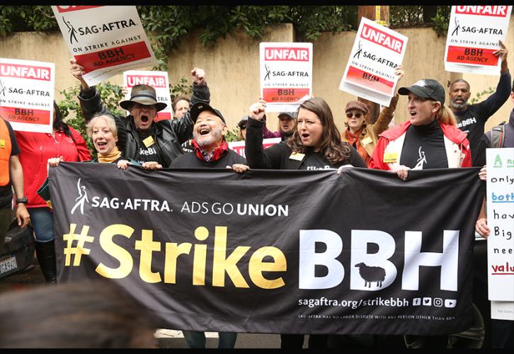 First row, from left, SAG-AFTRA National and L.A. Local Board member Ellen Crawford; VP, L.A. Clyde Kusatsu; EVP Rebecca Damon; and SecretaryTreasurer and L.A. Local President Jane Austin stand in a residential neighborhood with #StrikeBBH banner. 