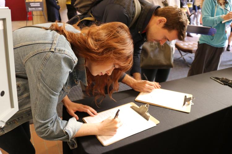 supporters signing in on a clipboard at the check-in table. 