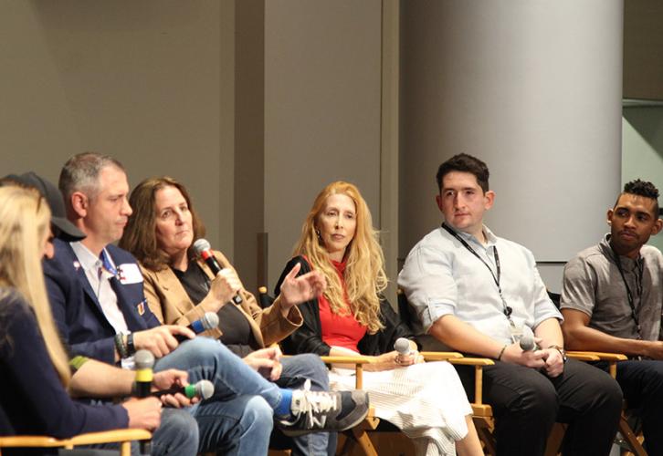 Six individuals sit in directors chairs with mics in their hands. 