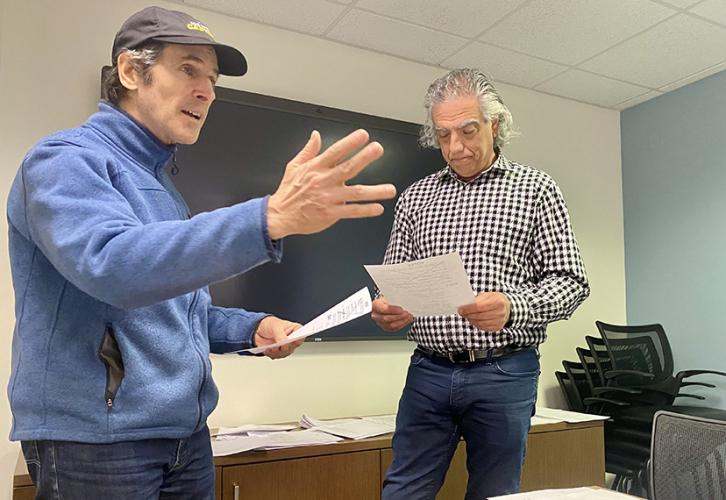 Bloom, in a cap and blue sweatshirt, gestures as he delivers his line. Rossi, in a black and white dress shirt and jeans, looks at his script.