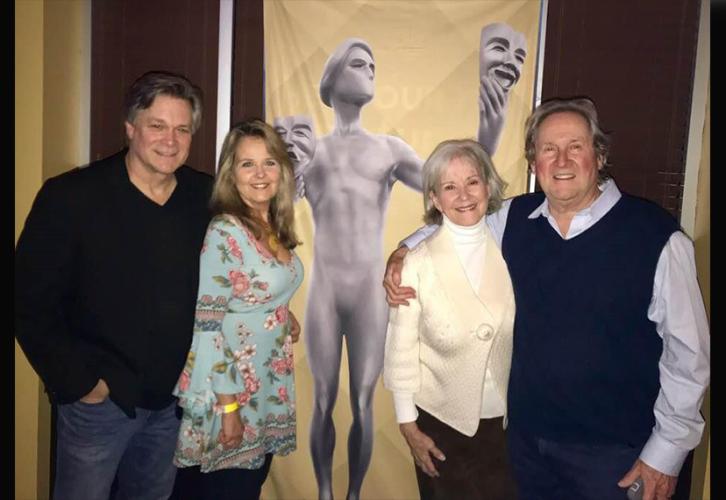 Foto grupal de las parejas de Reitz y McCabe con la pancarta de premios al fondo.