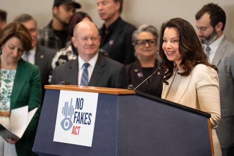 SAG-AFTRA President Fran Drescher speaking at a podium with many people in the background.
