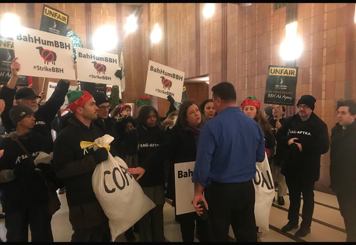 SAG-AFTRA Executive Vice President and N.Y. Local President Rebecca Damon, center, speaks with a security guard. Behind her stand members with bags of coal and signs.