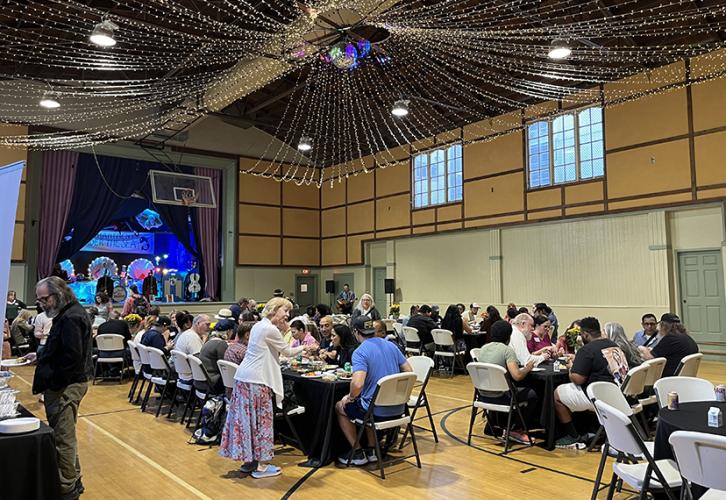 People sit at tables set up on a basketball court.