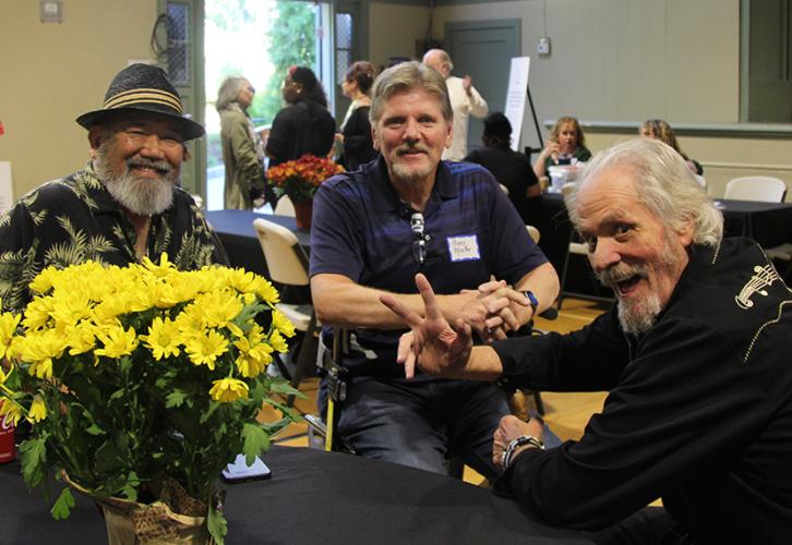 Kono, Mosher and Gainey sit at a table adorned with yellow flowers.
