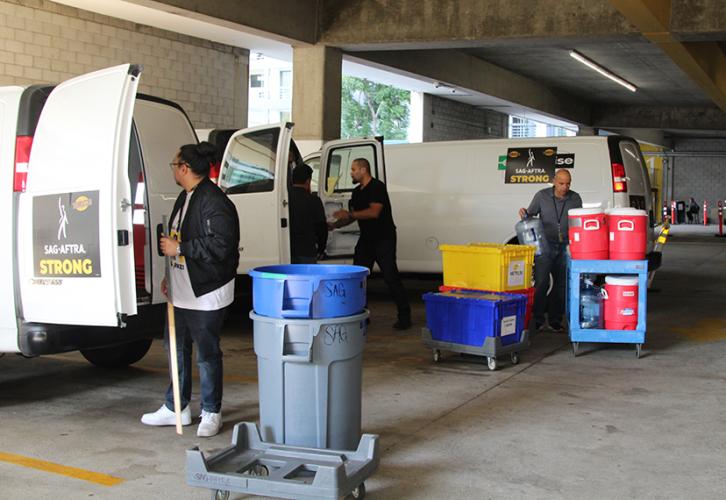 People unloading vans in a parking garage.