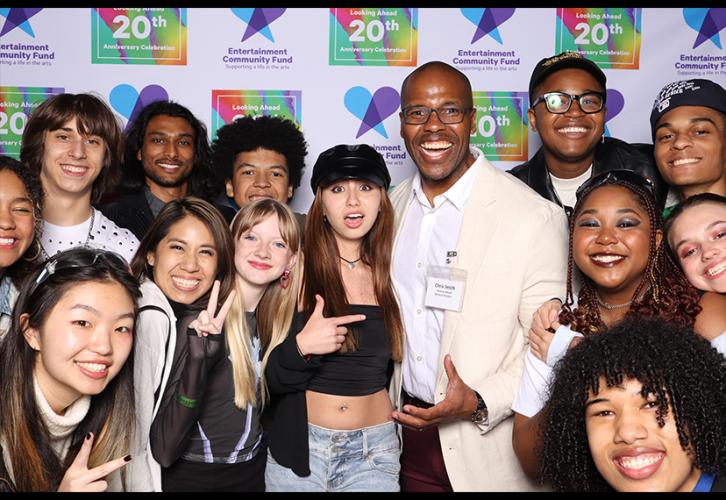 A group photo of people of all ages and ethnicities wearing various clothing styles posing in front of a Looking Ahead 20th Anniversary/Entertainment Community Fund step-and-repeat backdrop.