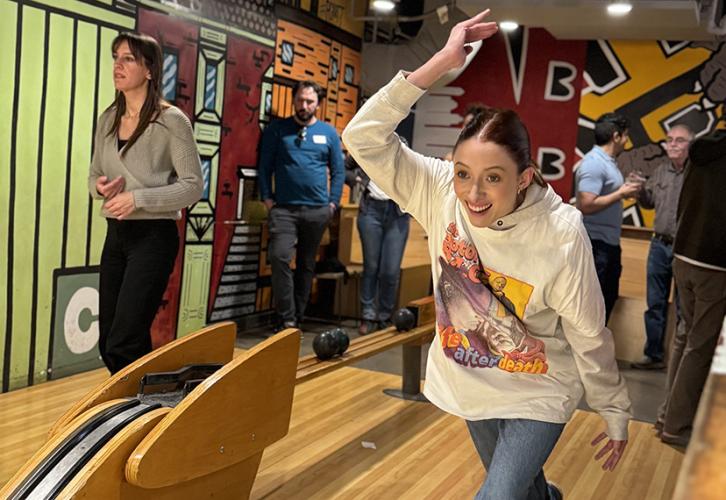 Caufield, wearing a colorful long-sleeve shirt, is caught mid-throw. Others watch in the background.