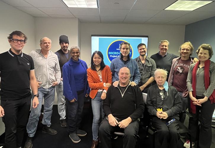 Members stand together for a group photo in a small room.