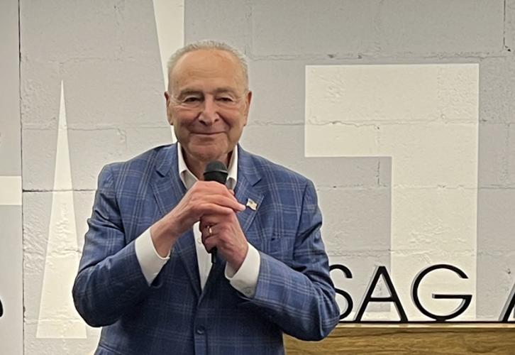 A man in a blue suit holds a microphone.
