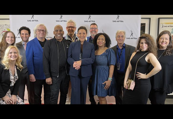 A diverse group of people pose in front of a white step-and-repeat with Sag-Aftra in black text.