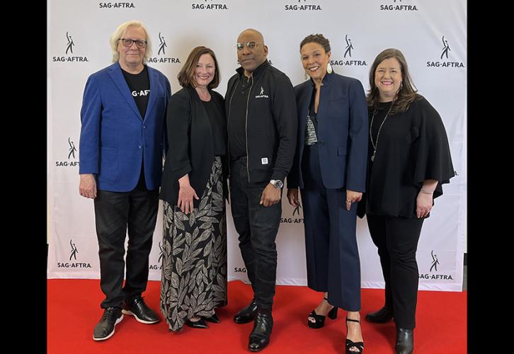 Five people smile in front of a white step-and-repeat with Sag-Aftra in black text on a red carpet.