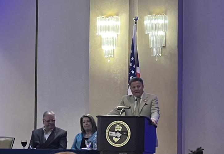 Wowkanech speaks at a podium emblazoned with the AFL-CIO logo. A man and woman sit at a table next to the podium.