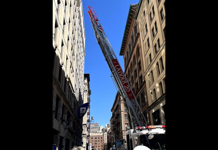 A fire engine's ladder goes up between two buildings. "Ladder 20" is written on the ladder.