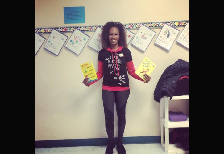 An African-American woman holds a Dr. Seuss book in each hand. 