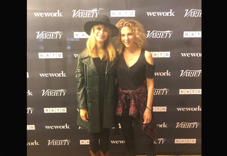 Two women stand for a photo in front of the panel backdrop.