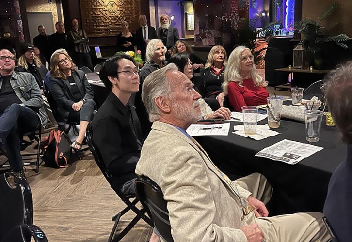 A group of attendees are watching the show from their tables.