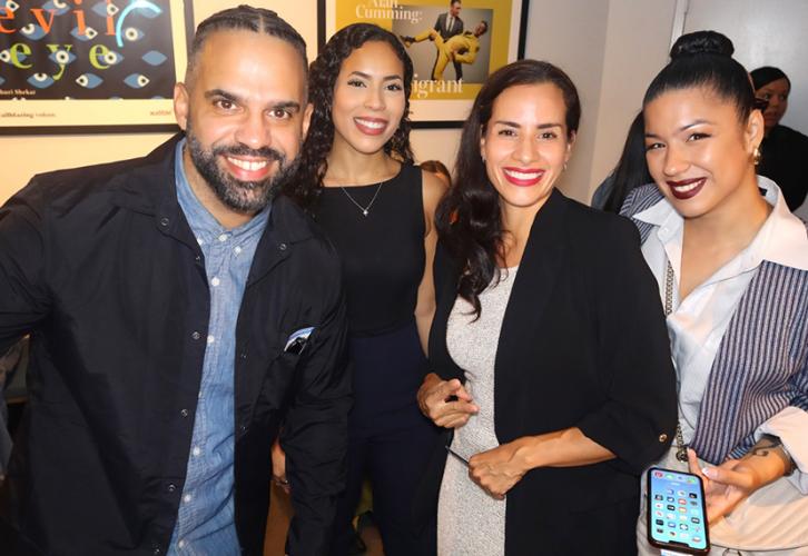  Four people in a crowd at the reception. They have arranged themselves in a line facing the camera. Some movie posters are visible behind them.